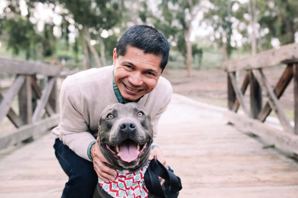 en man kramar sin hund på en bro